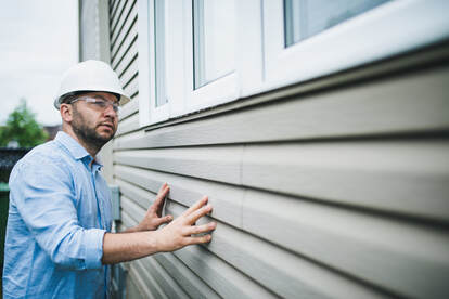Contractor inspecting windows and siding of a house